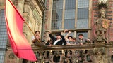 Jubelnde Männer mit roter Fahne auf dem Balkon des Bremer Rathauses