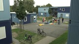 Die Flüchtlingsunterkunft "Das blaue Dorf" in Grohn, auf dessen Innenhof mehrere Kinder spielen.