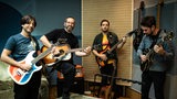 Pablo Held Trio und Nelson Veras: Vier Männer mit Gitarren und Bass stehen in einem Aufnahmeraum.