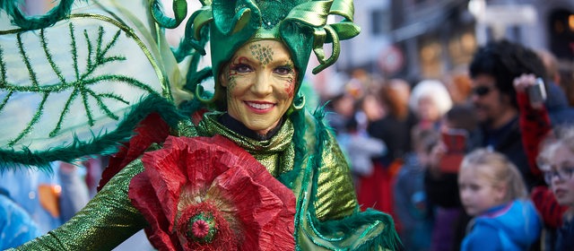 Frau mit grüner Maske und Kostüm beim Samba-Umzug