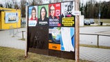 An einer Plakatwand sind Wahlplakate mehrerer Parteien.