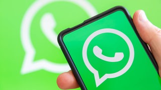 Hand hält Handy mit WhatsApp Logo